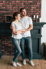 full length view of smiling man embracing girlfriend and looking away