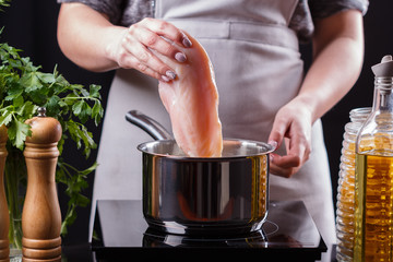 young woman in a gray apron boiled chicken breast