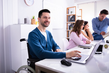 Disabled Man On Wheelchair Working In Office