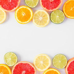 Colorful fruit double border of fresh citrus slices. Top view, flay lay over a white background with copy space.