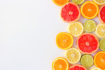 Colorful fruit side border of fresh citrus slices. Top view, flay lay over a white background with copy space.