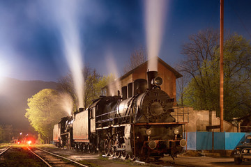 Soviet steam locomotives with working steam engines at night. Ukrainian Carpathians, Europe.