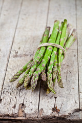 Bunch of fresh raw garden asparagus on rustic wooden table background. Green spring vegetables.