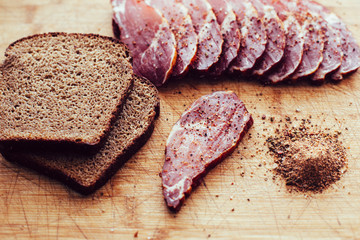 Smoked meat, pepper. Slices of smoked meat with black bread on a wooden board.