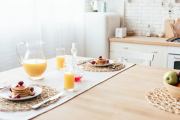 Fototapeta na wymiar served table with pancakes, syrup and orange juice