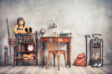 Vintage old typewriter, lamp, carnival mask, globe on antique table, chair, Teddy Bear with photo camera, retro clock, books, fiddle, keys on shelf, telephone, souvenirs, shoes, cane, backpack, bow 