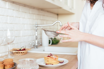 cropped view of woman using sieve while preparing breakfast in kitchen