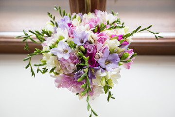 Delicate bouquet of multi-colored freesia on the background of the window
