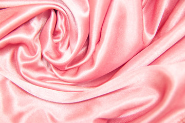 textile and texture concept - close up of crumpled silk pink wavy fabric background.