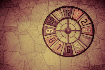 Beautiful symbolic clock on a wall with a stone texture. Toned photo with vignetting.Place for text. Artistic background.
