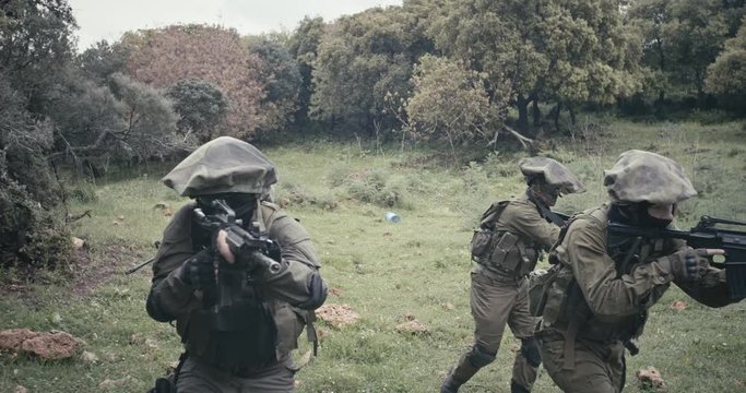 Squad of fully armed commando soldiers during combat in a forest scenery