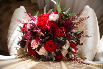 Exquisite bridal bouquet of red and pink roses on the chair