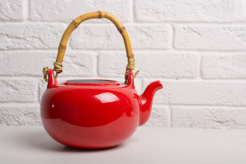 Red teapot closeup on the table.