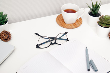 Workspace with laptop, notebook, sketchbook, succulent, cup of tea on white background. Flat lay, top view office table desk. Freelancer working place. copyspace