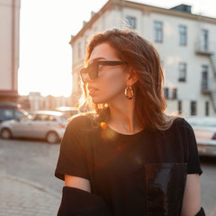 Stylish pretty attractive young hipster woman in trendy dark sunglasses in a stylish black T-shirt...