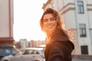 Attractive pretty cheerful young woman in fashionable clothes walks around the city in bright sunny...