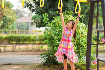 Little cute girl hanging the bar at the park. training learning skill, exercise.