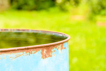 Old metal barrel filled to the brim with rain water for watering beds