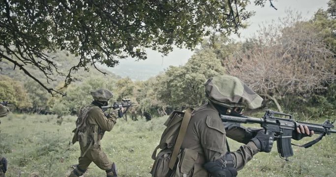 Squad of fully armed commando soldiers during combat in a forest scenery
