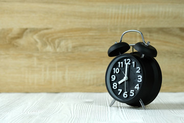 Black retro alarm clock on wood table, time concept.
