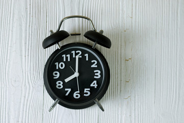Black retro alarm clock on wood table, time concept.