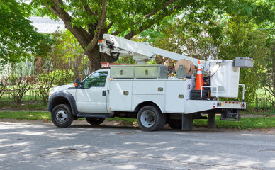 Parked telecommunications vehicle on shaded neighborhood street.