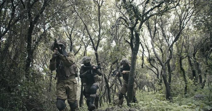 Squad of fully armed commando soldiers during combat in a forest scenery