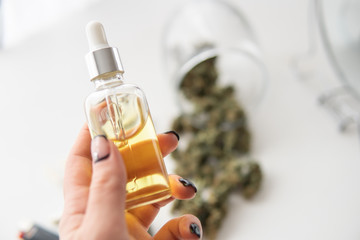 oil Cannabis CBD in pipette women hand, marijuana extract on white background, close up, weed...