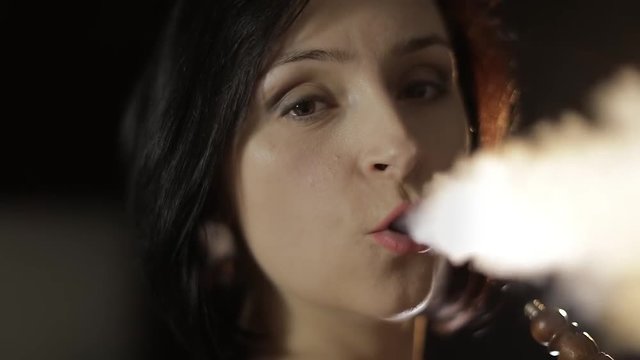 Beautiful, young woman smoking hookah. Attractive girl smoking flavored tobacco
