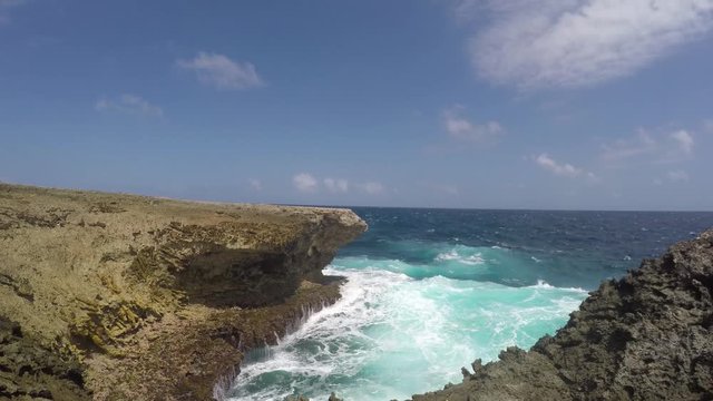 A breaking waves and a blowhole spilling sea water due to the rough surf and waves at a cliff of the east coast of tropical Bonaire island in the caribbean