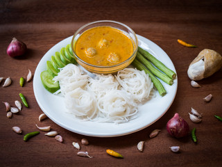 Thai Rice Noodles in Fish Curry Sauce with ingredient on wooden table.