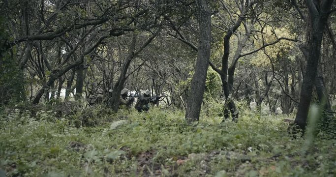 Squad of fully armed commando soldiers during combat in a forest scenery