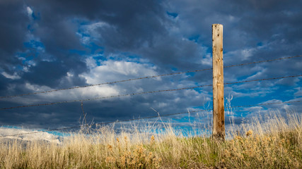Rusty barbed wire fence against western skies in the American West