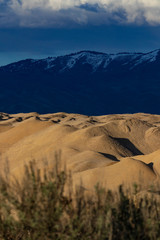Sun and shade on sand/gravel quarry hills, with foothills and mountains of Boise in background
