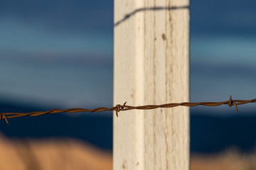 Close up view of rusty barbed wire fence against western backdrop