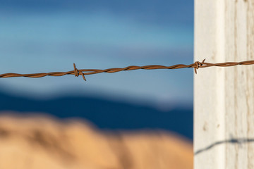 Close up view of rusty barbed wire fence against western backdrop