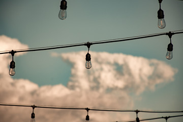 hanging electric lights with clouds in the background