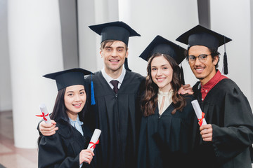 smiling group on students looking at camera while holding diplomas