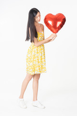 Fototapeta na wymiar Asian young woman in yellow dress hold red balloon heart. Young woman holding it with being excited and surprised holiday present isolated white background.concept love surprise valentine day.