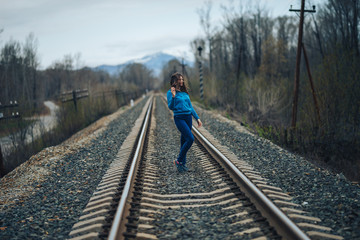 woman with dark hair standing on railway track, wind in hair