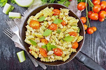 Fusilli with chicken and tomatoes in pan on board top