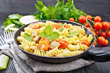 Fusilli with chicken and tomatoes in pan on dark board