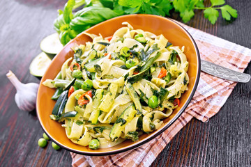 Tagliatelle with green vegetables on dark board