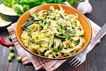 Tagliatelle with green vegetables on wooden board