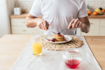 Obraz na płótnie Canvas partial view of man eating pancakes in kitchen