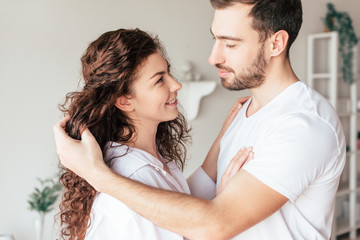 Fototapeta premium smiling happy couple gently touching each other in bedroom