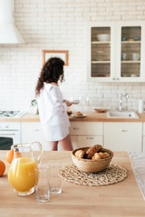 selective focus of woman preparing breakfast with orange juice and croissants on foreground