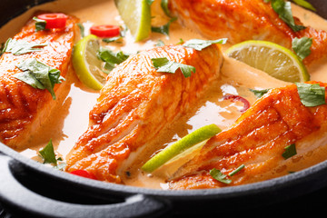Poached Salmon in a Thai coconut curry close-up on the table. horizontal