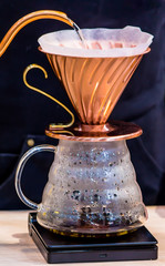 Showcase Drip coffee maker and Barista pouring water on ground coffee with filter.