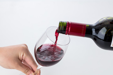 白背景に女性の手でワイングラスを持って赤ワインを注ぐ瞬間ソムリエパーティーバー
